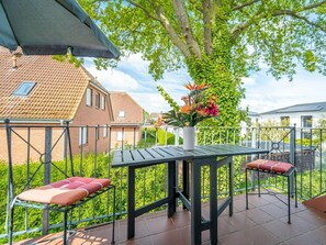 Eine Außenpatio mit Tisch und Stühlen, einem Blumentopf und Blick auf benachbarte Häuser.