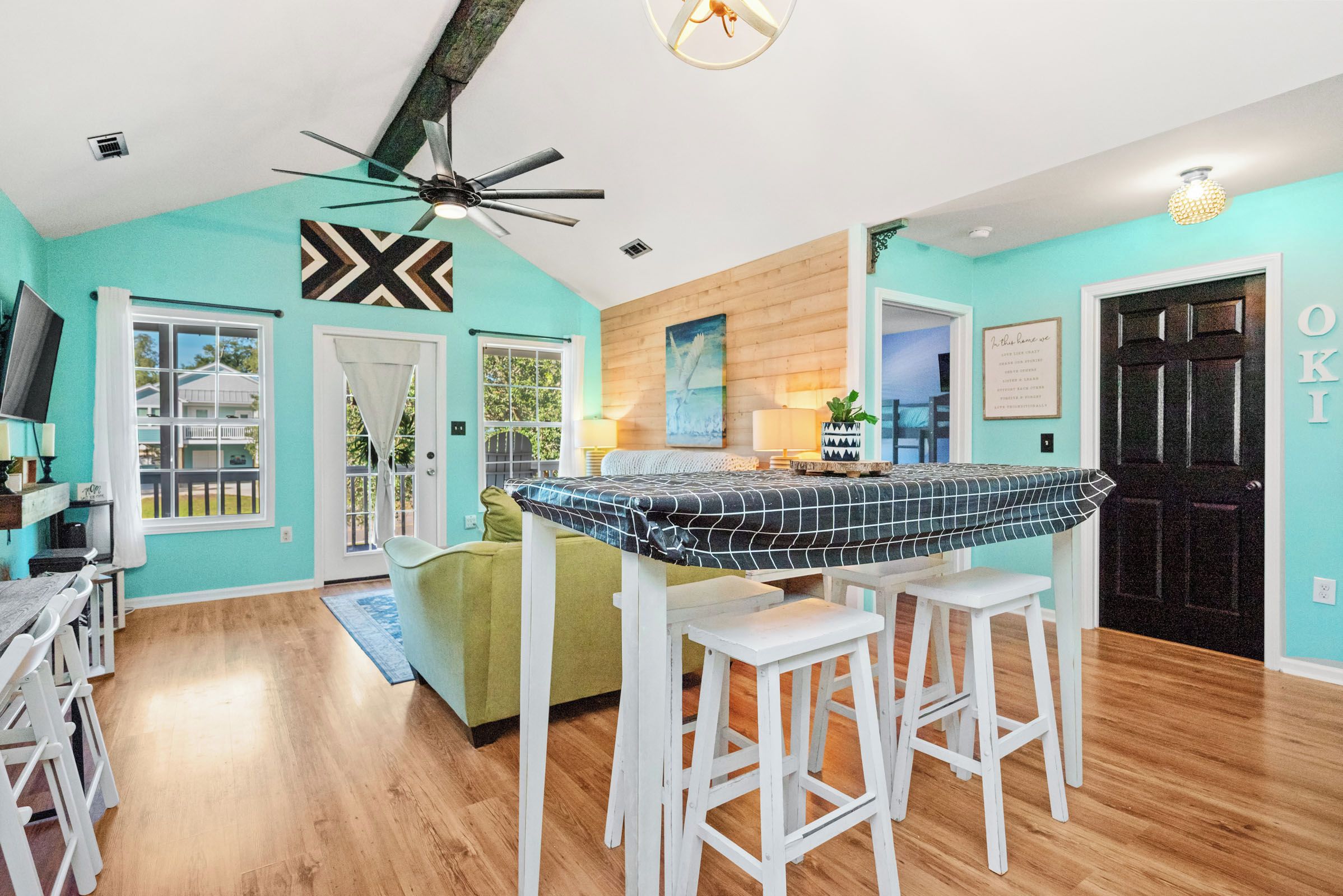 A modern kitchen with a central island, white bar stools, and a ceiling fan.