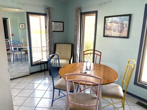 Un coin repas avec une table ronde, quatre chaises et une fenêtre avec des rideaux.