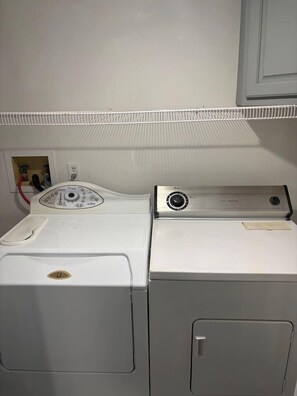 Eine weiße Waschmaschine und ein Wäschetrockner stehen nebeneinander in einem Hauswirtschaftsraum.