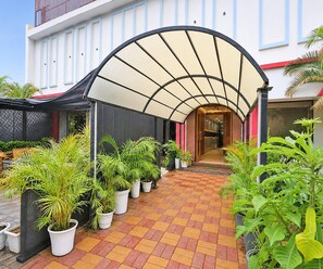 A hotel entrance with a covered walkway, potted plants, and a tiled floor. - Classic Hotel U Turn & Restaurant (Dr. Ambedkar Nagar)