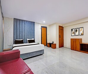 Une chambre à coucher moderne avec un lit, des tables de chevet, une armoire et un fauteuil rouge.