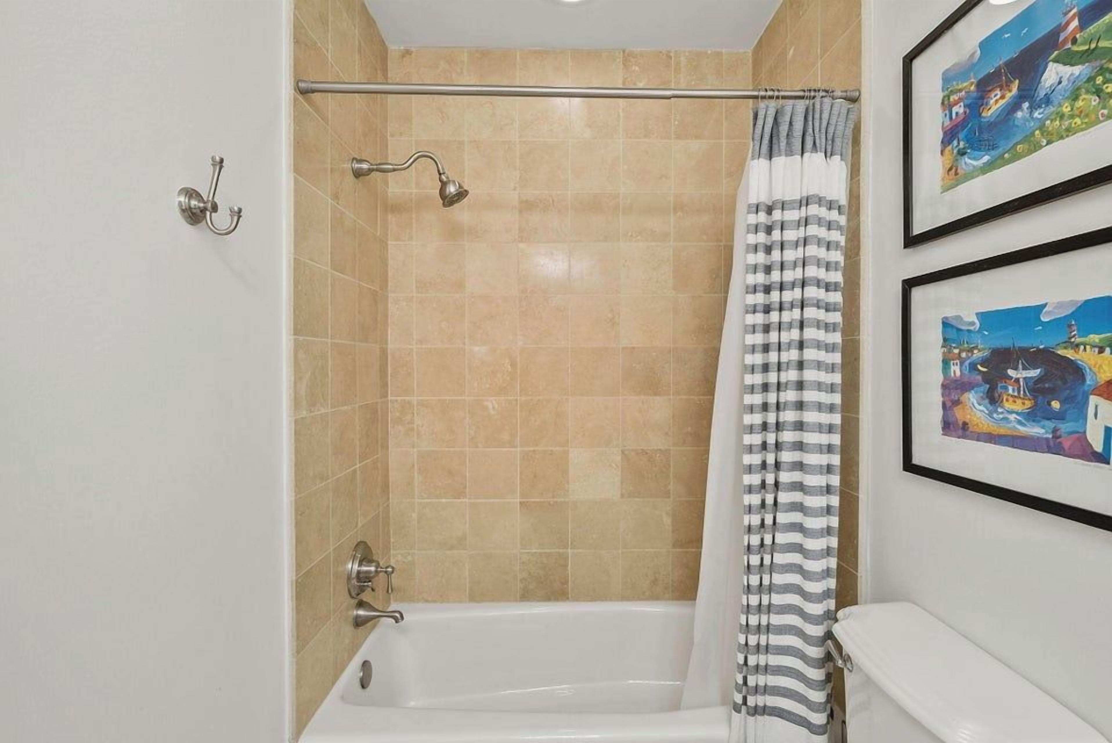 A bathroom with a bathtub, a shower curtain, and a toilet.