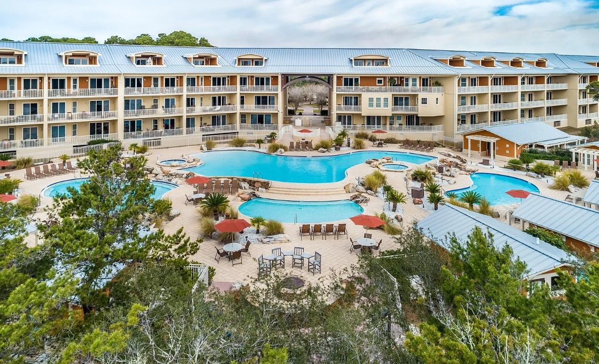 A hotel with a large central pool, multiple smaller pools, and outdoor seating areas.