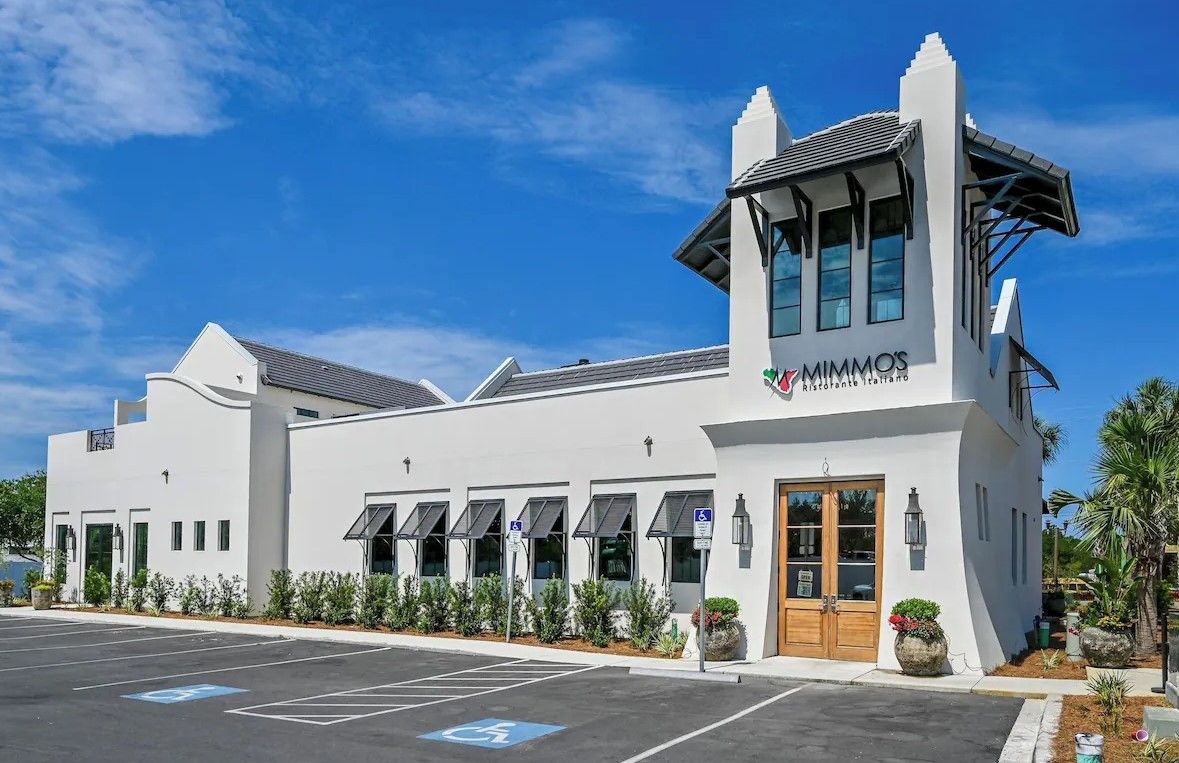 A modern building with a white facade, multiple windows, and a prominent entrance.
