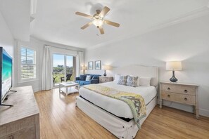 Ein Schlafzimmer mit Bett, Nachttischen, einem Deckenventilator und Blick ins Freie.