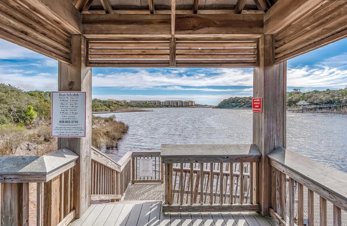 A wooden pier with a view of a river and distant buildings.