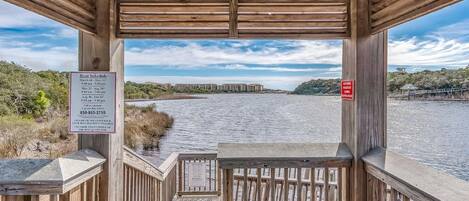 Un muelle de madera con vista a un río y edificios lejanos.