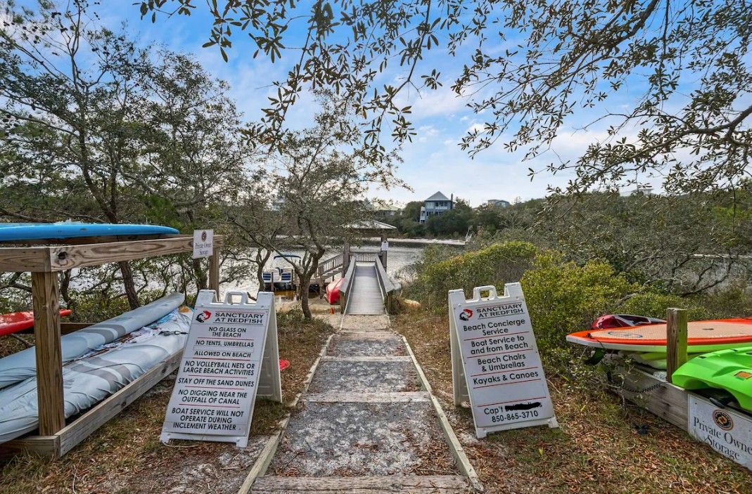 A beach access path with signs indicating beach rules and services.