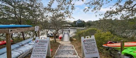 A beach access path with signs indicating beach rules and services.