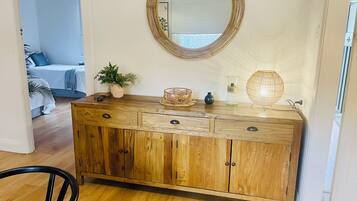 A wooden cabinet with a mirror above it, a small plant, and a lamp on the countertop.