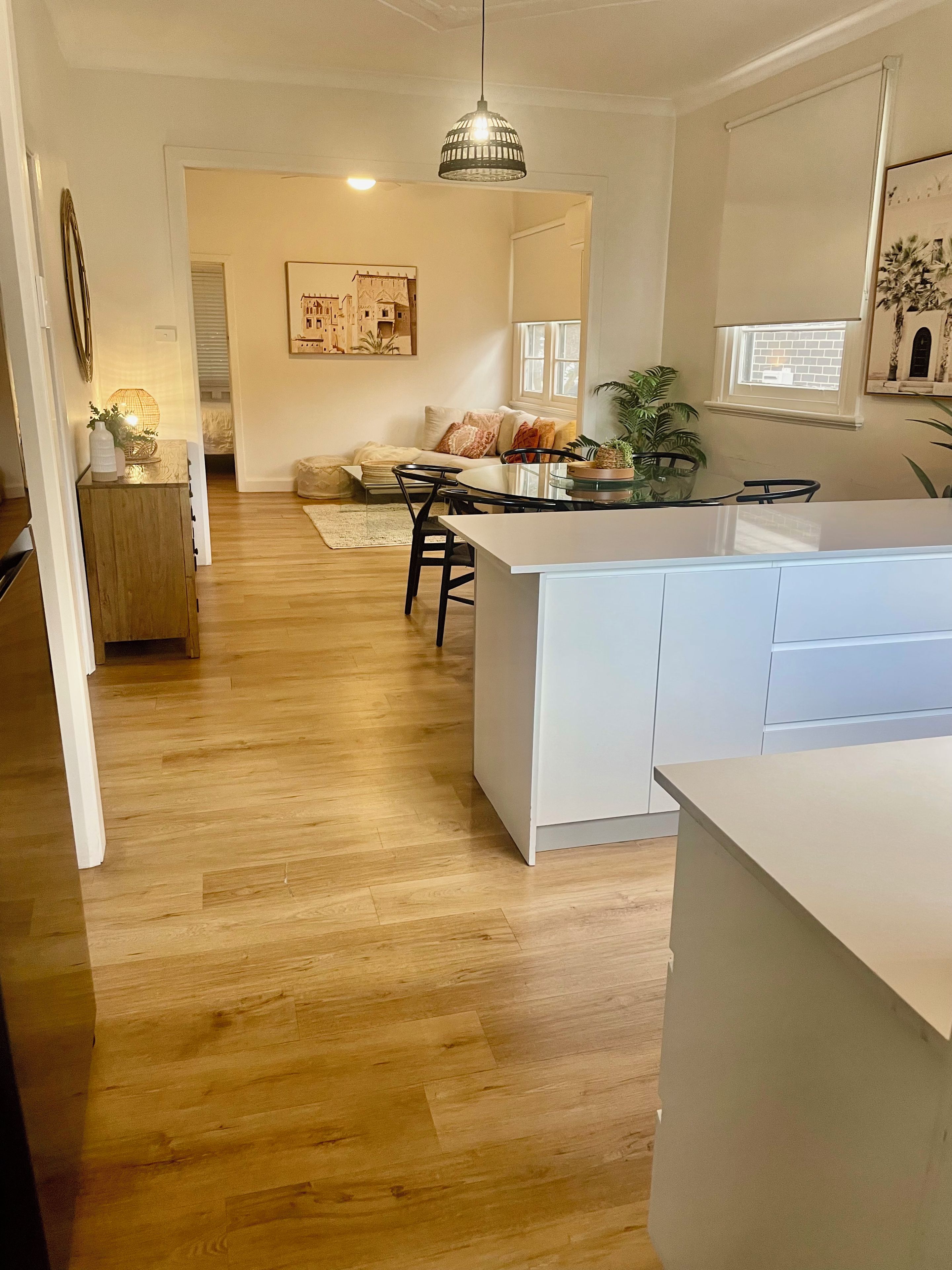 A modern kitchen with a central island, wooden flooring, and a dining area with a sofa and chairs.