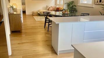 A modern kitchen with a central island, wooden flooring, and a dining area with a sofa and chairs.