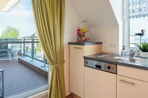 Una cocina moderna con lavavajillas incorporado, ventana con vistas al exterior y balcón con mobiliario para disfrutar al aire libre.