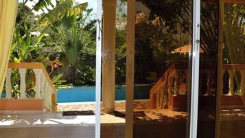 A covered outdoor area with a pool, palm trees, and a wooden structure.