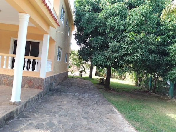 A building with a stone-paved pathway leading to a covered entrance with white columns.
