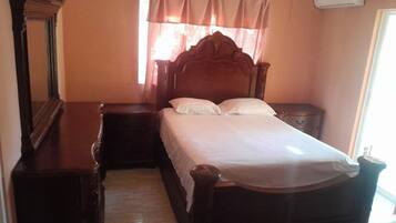 Un dormitorio con una cama de madera, una mesita de noche, un aparador y una ventana con cortinas.