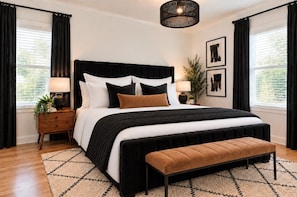 Quarto com cama grande, mesas de cabeceira, um banco e luminária pendente.