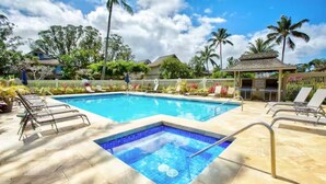 En swimmingpool med liggestole og et lille område med jacuzzi.