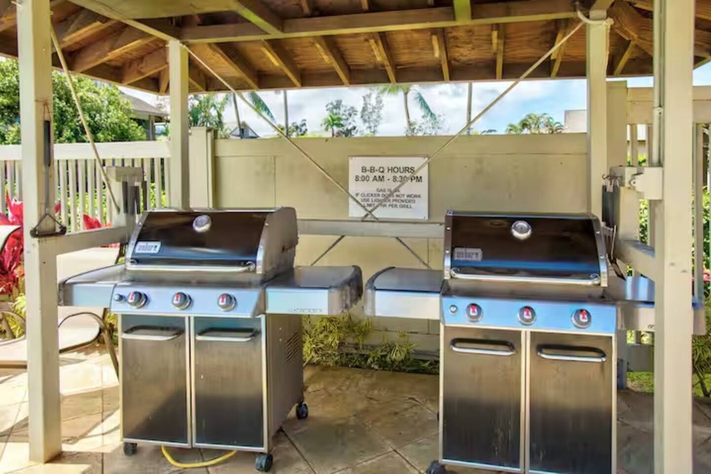 Zwei Grillplätze unter einem Überdachung mit einem Schild, das die Grillzeiten angibt.