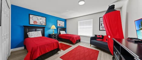 A bedroom with two beds, a desk, and a TV.