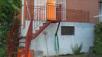 Um edifício de tijolos com uma escada de metal vermelha que leva a uma porta.