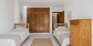 A bedroom with two beds, a wardrobe, and a mirror.