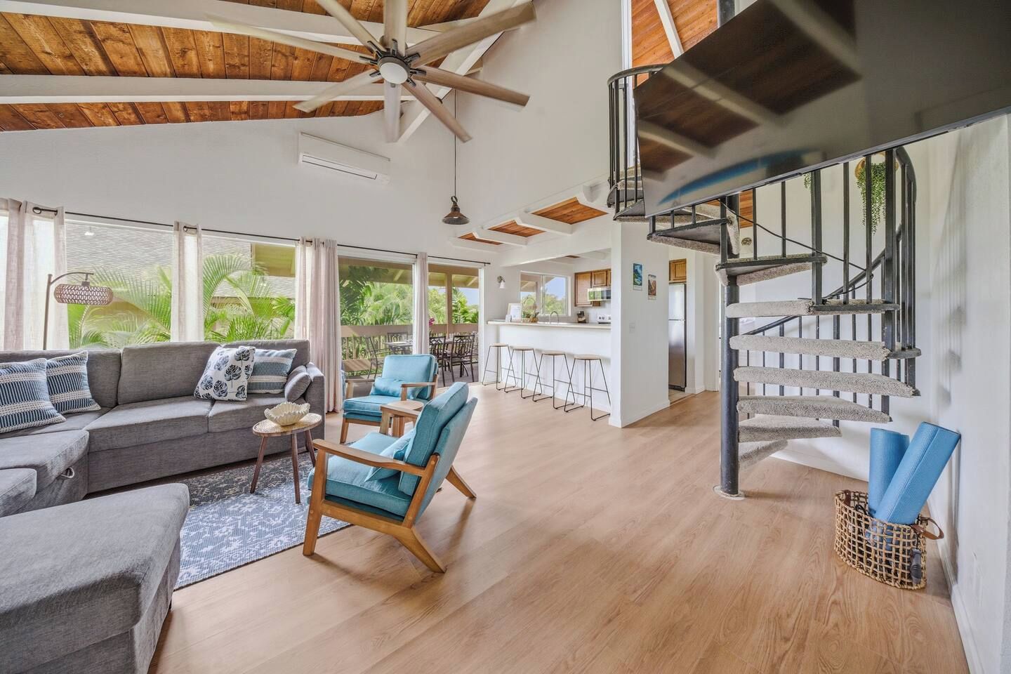 Ein geräumiger Wohnbereich mit einer Couch, Sesseln und einer Treppe.