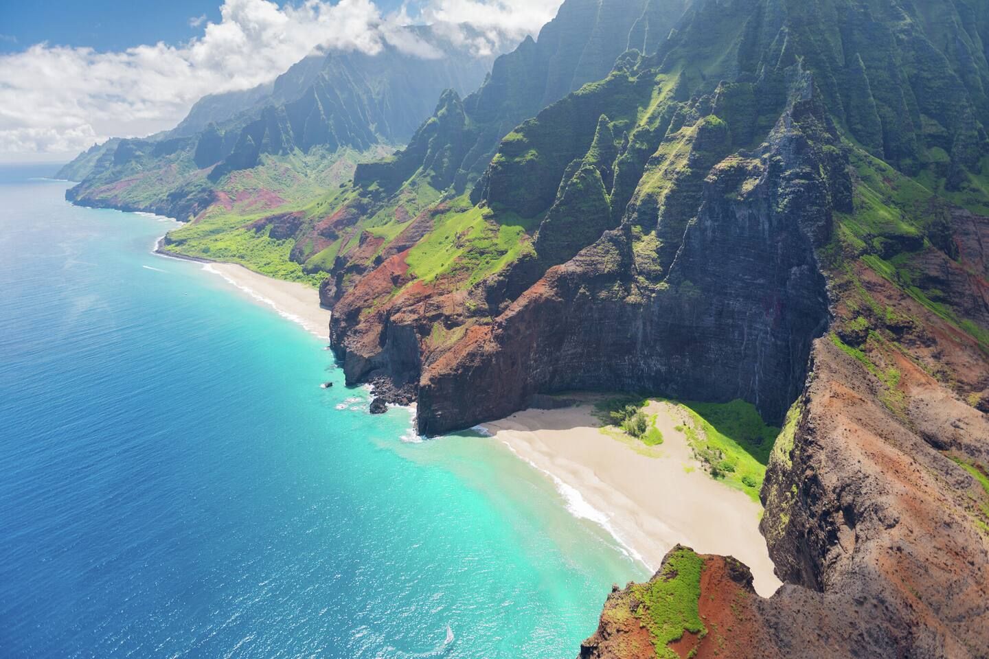 Un paysage côtier avec une plage, des falaises et un océan bleu limpide.