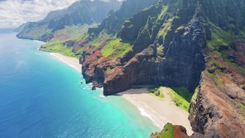 A coastal landscape with a beach, cliffs, and a clear blue ocean.