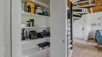 Una cocina moderna con armarios blancos, cafetera, olla de cocción lenta y procesador de alimentos.