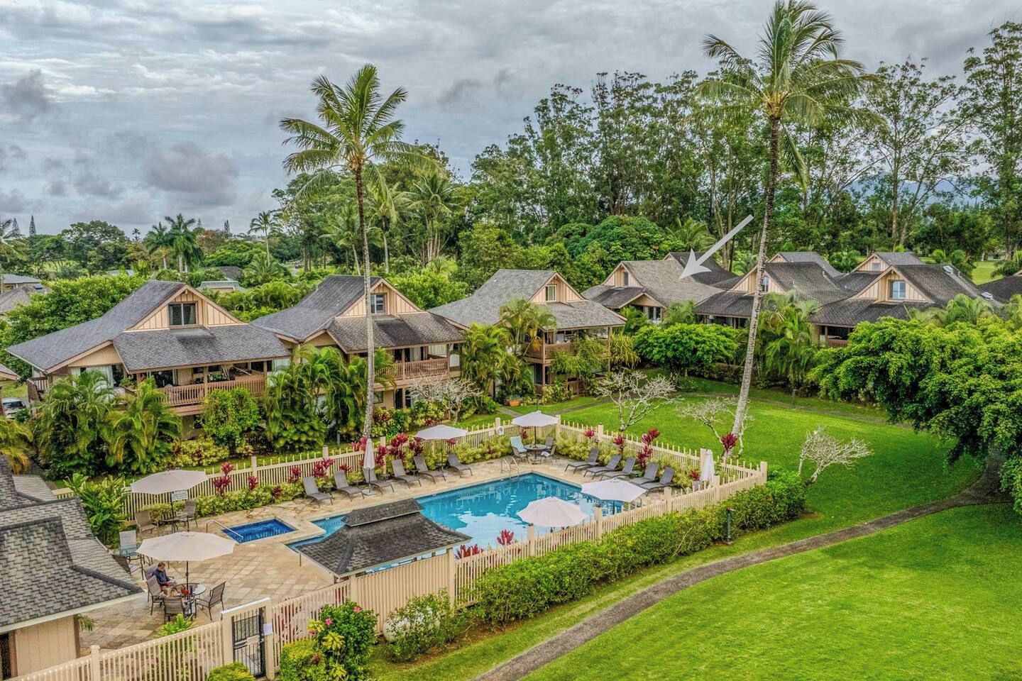 Ein Resort mit mehreren Bungalows, einem Swimmingpool und üppiger Vegetation.