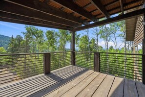 Eine Holzterrasse mit Metallgeländer mit Blick auf ein bewaldetes Gebiet.