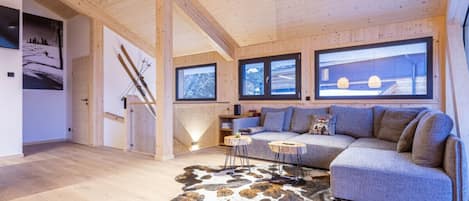 Een modern interieur met een houten plafond, een bank, een salontafel en een vloerkleed met een koeienhuidpatroon.