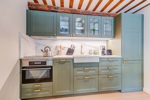Eine Küche mit Türkis-Schränken, einem eingebauten Ofen und einem Holzbalken an der Decke.