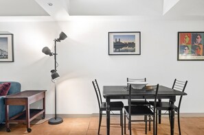 A dining area with a table, chairs, a floor lamp, and artwork on the walls. - Melbourne 1-bed Apartment Flinders Street (Melbourne)