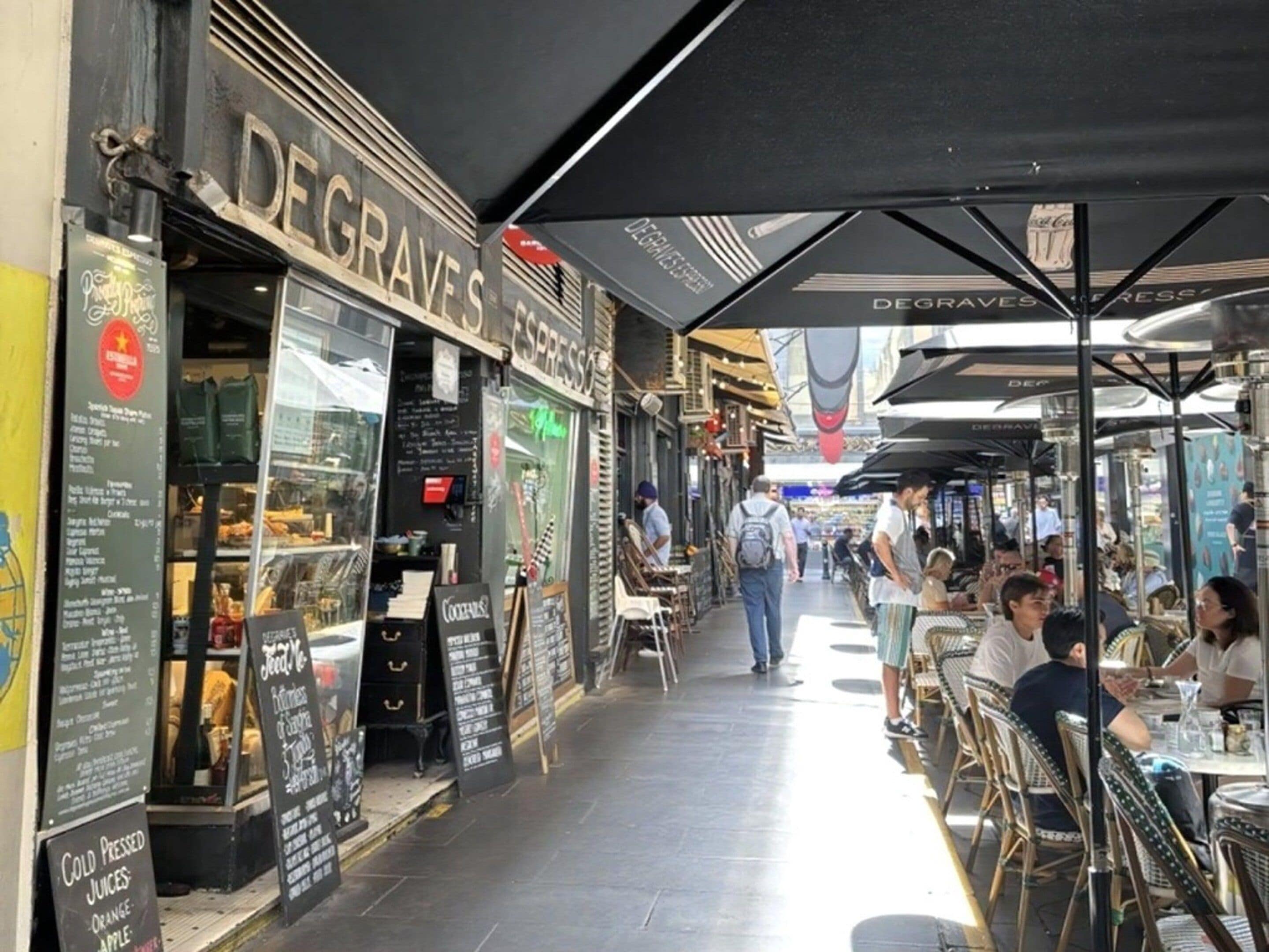 An outdoor café with tables and chairs, a sign for 'DEGRAVES EXPRESS', and a menu board.
