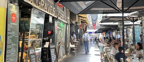 Un café en plein air avec des tables et des chaises, une enseigne indiquant « DEGRAVES EXPRESS » et un panneau affichant le menu.