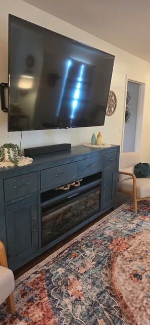 A flat-screen TV mounted on a dark wooden entertainment center with drawers and a built-in shelf.