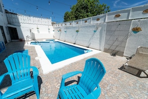 A swimming pool with two blue chairs and a patterned floor. - Beautiful 3-bedroom apartment,3 Min walk to the Beach,Costambar Puerto Plata,DR (Puerto Plata)