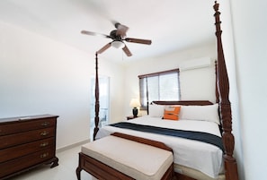 A bedroom with a four-poster bed, a ceiling fan, a dresser, and a window with blinds. - Beautiful 3-bedroom apartment,3 Min walk to the Beach,Costambar Puerto Plata,DR (Puerto Plata)