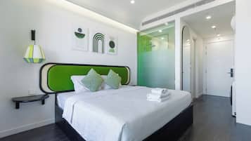 A modern hotel room with a green headboard, white bedding, and a small bedside table.