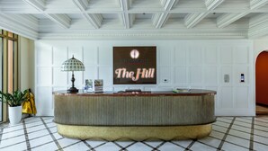 Un espace d’accueil avec un comptoir d’enregistrement, une plante en pot et un panneau indiquant : « Sun Grand City Hillside Residence, The Hill ».
