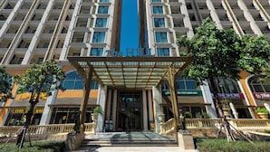 L’entrée d’un hôtel, avec une bande bleue centrale, plusieurs étages et des boutiques situées de part et d’autre.