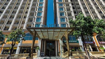 A hotel entrance with a central blue stripe, multiple floors, and surrounding shops.