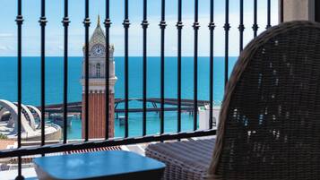 A balcony with a view of a clock tower and a bridge over water.