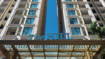 A hotel facade with a central entrance, multiple balconies, and a clear sky.