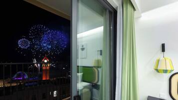 Un balcón con vistas a fuegos artificiales, una torre de reloj y un edificio con ventanas iluminadas.