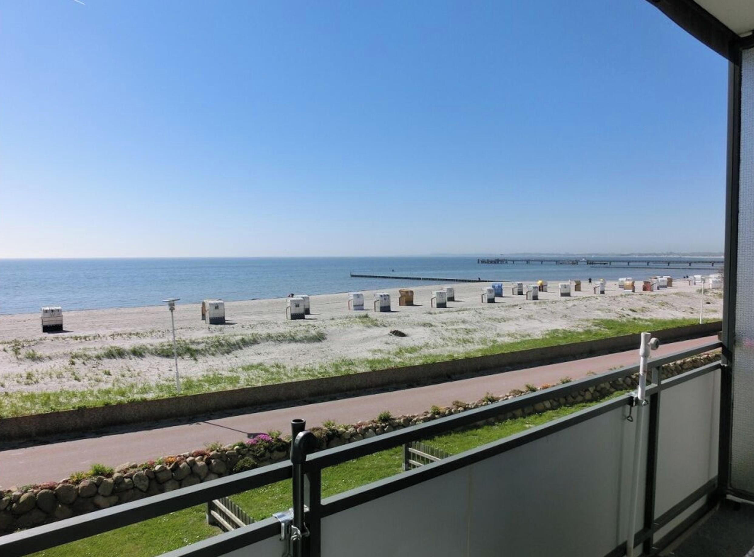 A balcony with a view of a beach and a pier.