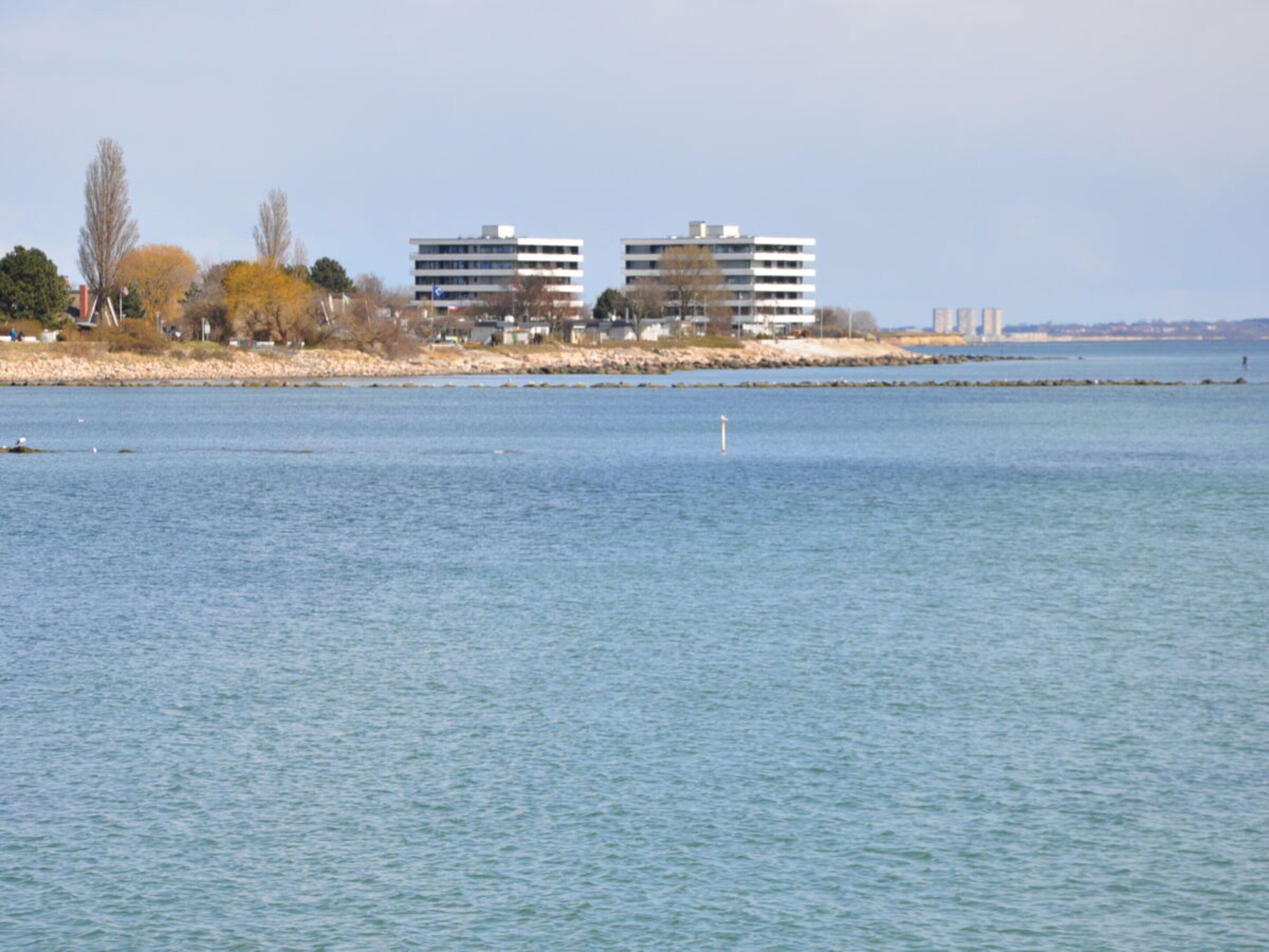 Blick auf das Wasser mit Gebäuden und einer ruhigen Wasseroberfläche.